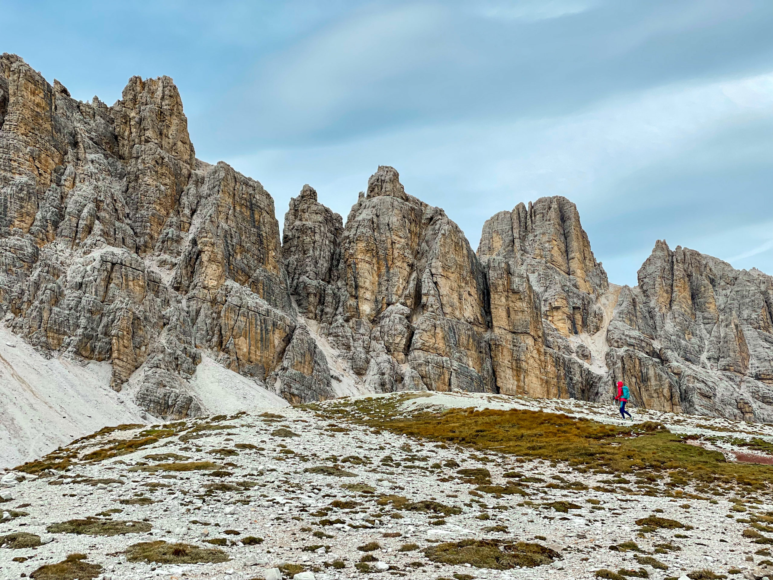 Ewa idzie po płaskim terenie, a w tle widać poszarpane szczyty Dolomitów- zejście z ferraty degli Alpini