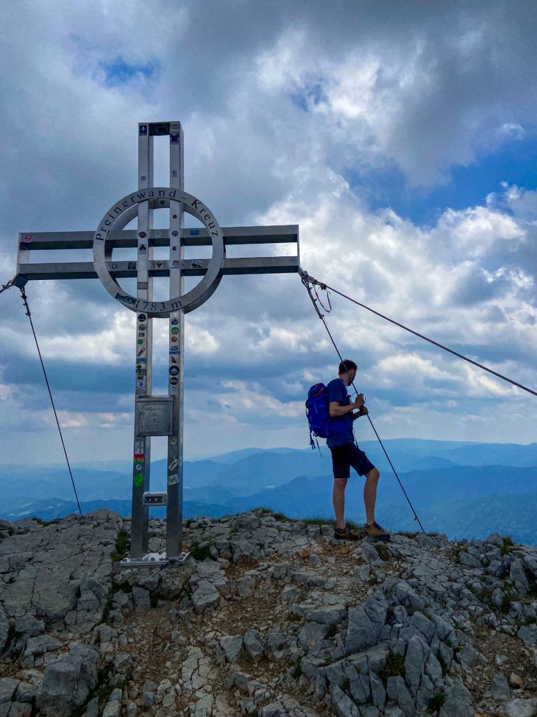Marcin stoi przy krzyżu na szczycie Preinerwand po zakończeniu ferraty Haidsteig, Austria