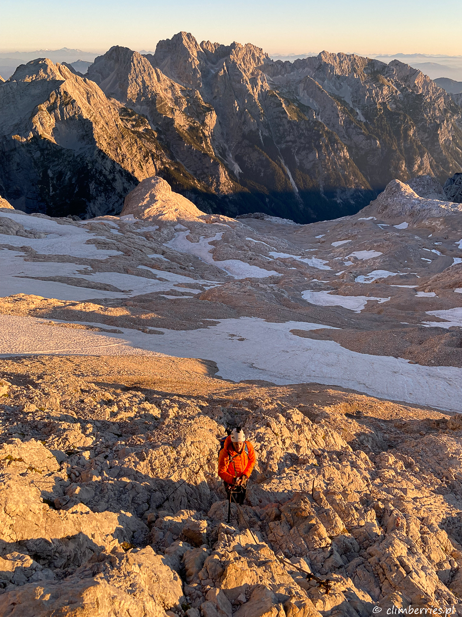 Góry skąpane w pomarańczowym świetle wschodzącego słońca i Marcin podczas wspiaczki na Triglav