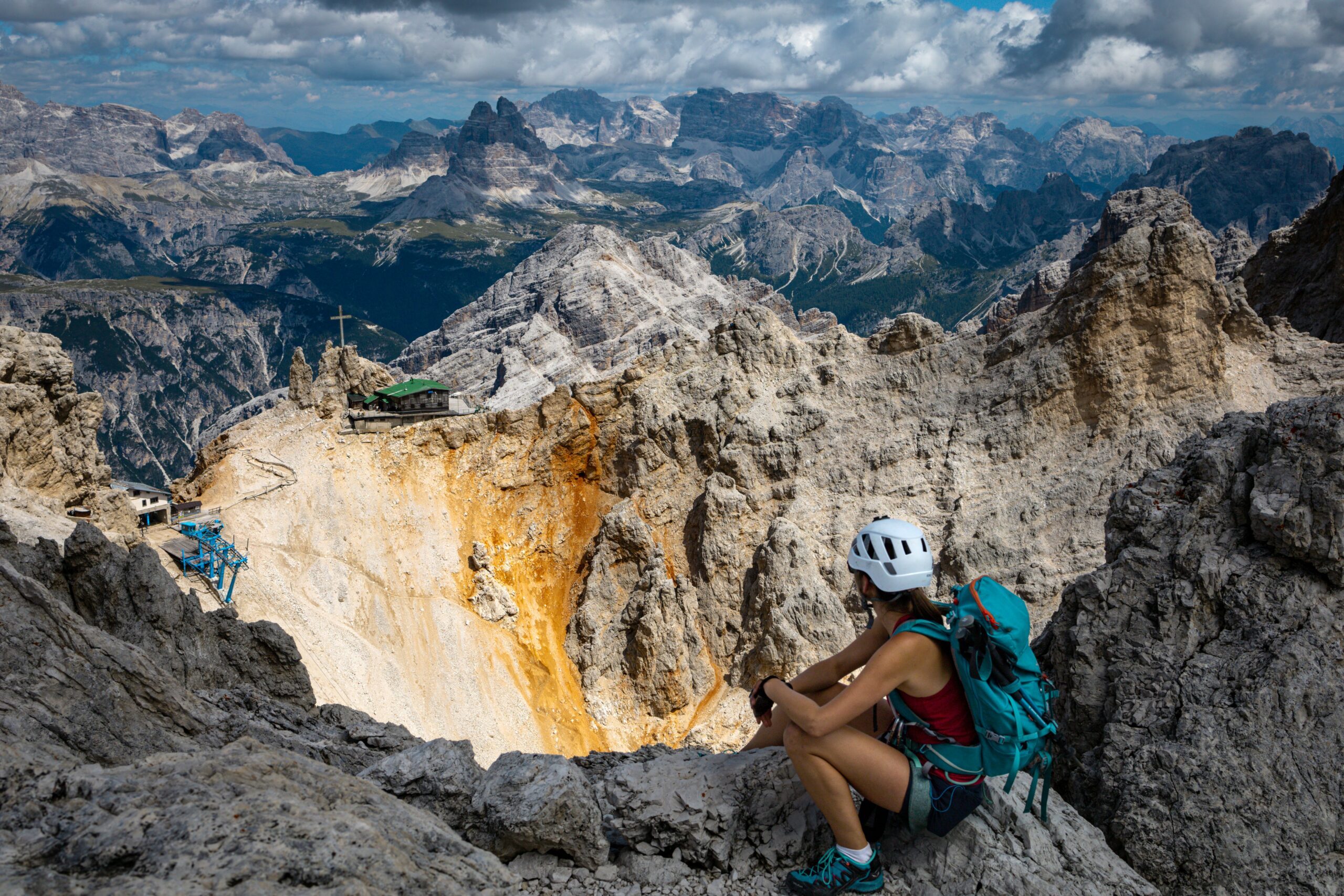 Ewa siedzi na skałach na szczycie Cristallino z widokiem na końcówkę ferraty Dibona