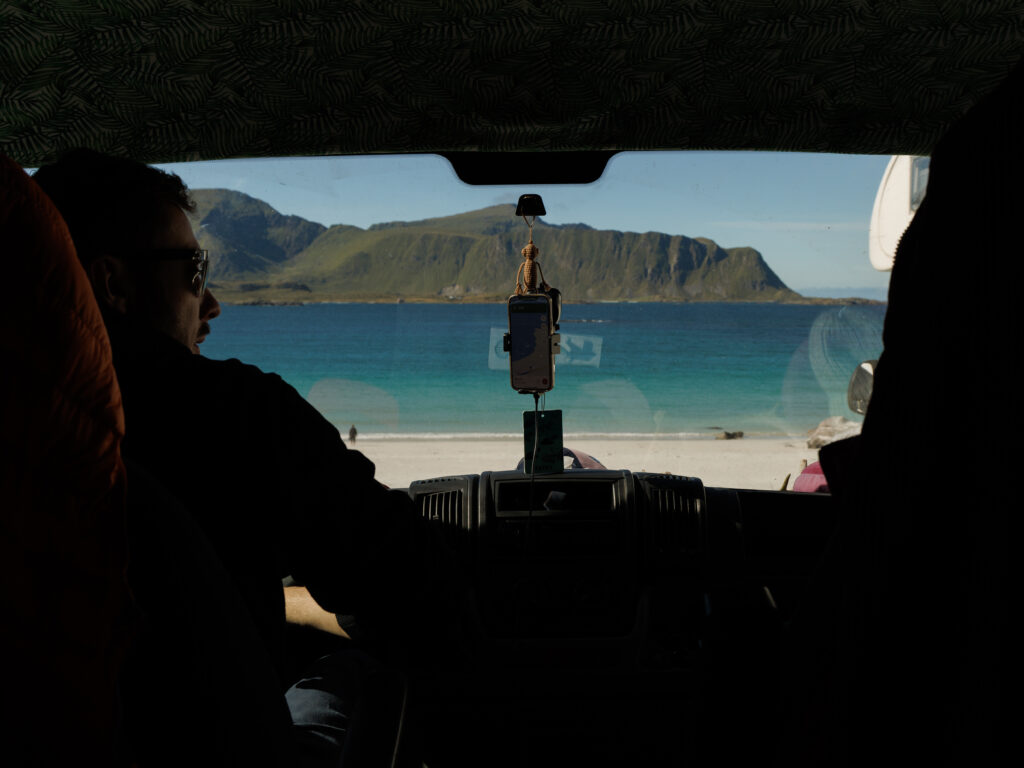 Zdjęcie robione z wnętrza samochodu. widac Marcina oraz widok na plażę i morze przez przednia szybę