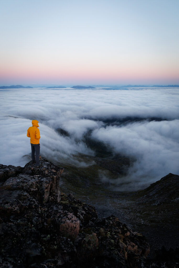Marcin na szczycie Keipien, a w tle chmury oraz widok na dalekie szczyty
